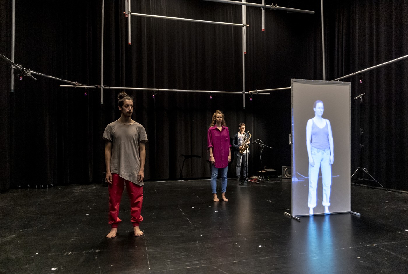 Dancers, a musician and a remotely projected performer in the telematic stage setup.