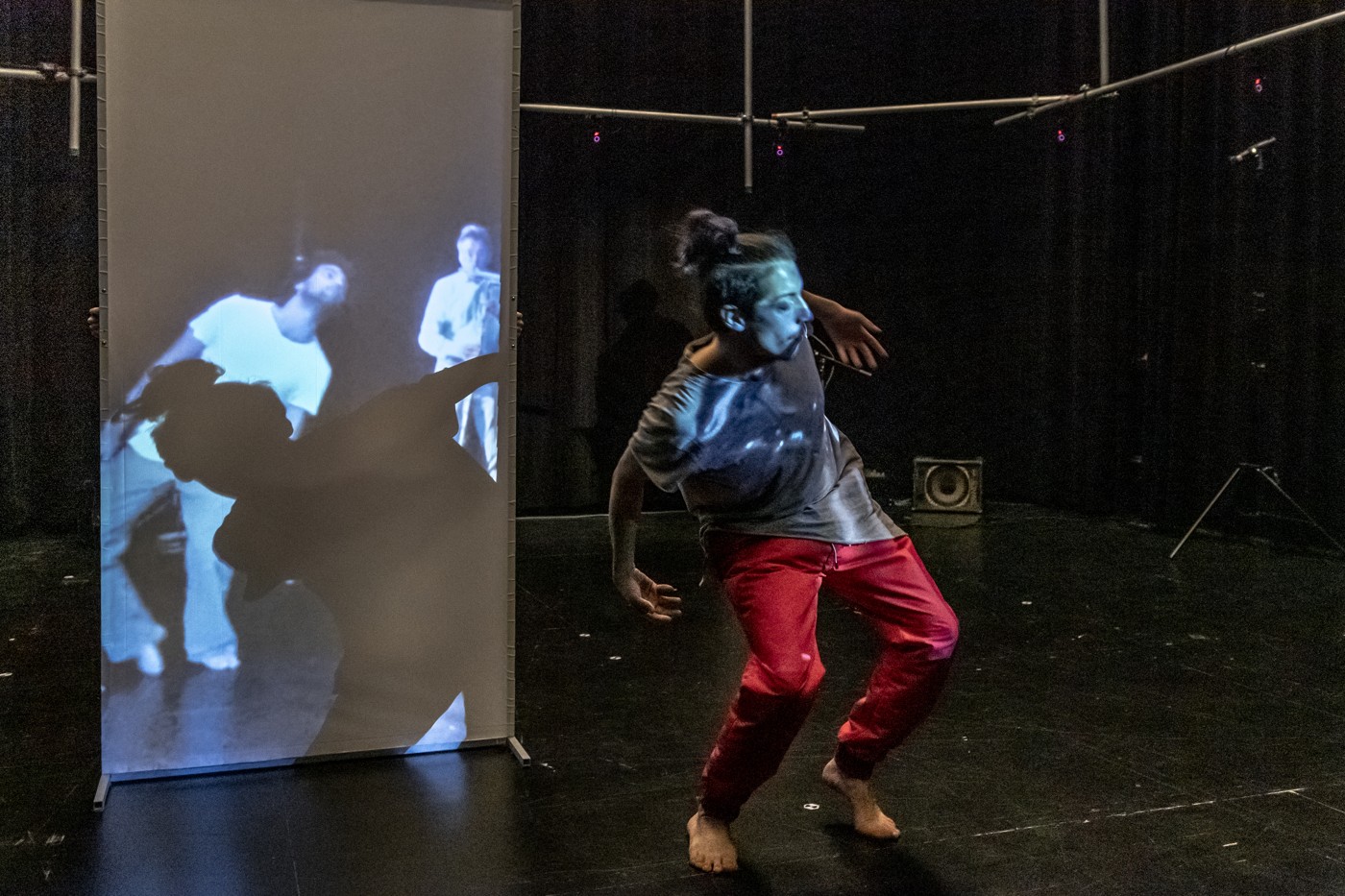 A dancer moving beside a screen showing remote performers.